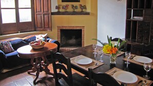 A dining area with a fireplace, wooden furniture, and a table set for two. - Casita La Chimenea (Antigua Guatemala)