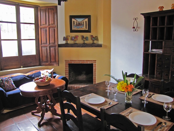 Comedor con chimenea, muebles de madera y una mesa dispuesta para dos.