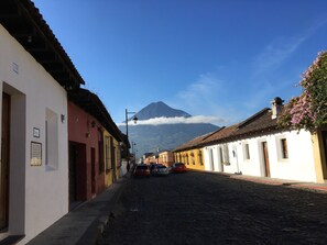 Una calle empedrada flanqueada por edificios tradicionales, con una montaña al fondo y un cielo despejado.