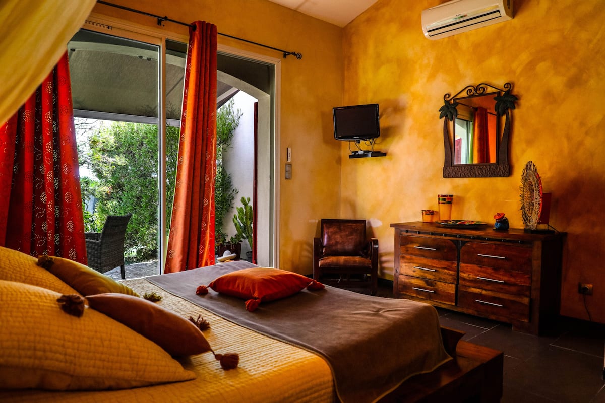 Ein Zimmer mit Bett, Stuhl, Kommode und Fernseher.