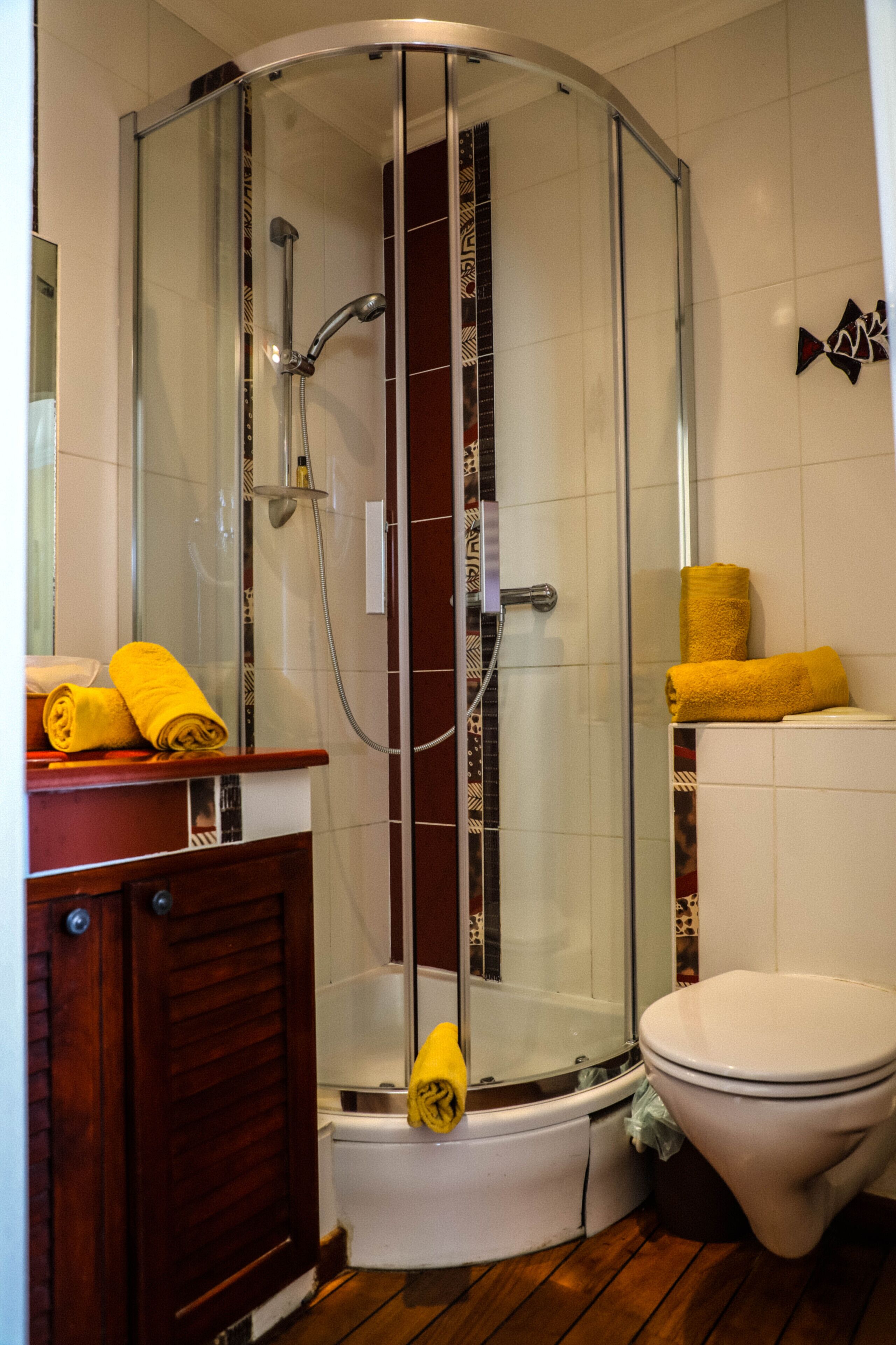 A bathroom with a glass-enclosed shower, a wooden vanity, and a toilet.