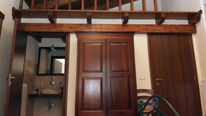 Un escalier en bois menant à un deuxième étage, une porte en bois et une salle de bain avec un lavabo et un miroir.