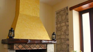 Une cheminée en pierre agrémentée de deux lanternes, une table en bois sur laquelle est posé un vase de fleurs, et un mur en pierre.