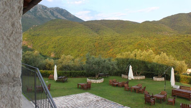 Une terrasse avec des meubles d’extérieur, une zone dallée de pierres et une vue sur un paysage montagneux.