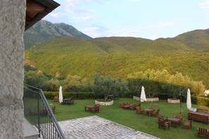 Une terrasse avec des meubles d’extérieur, une zone dallée de pierres et une vue sur un paysage montagneux.