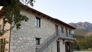 Un bâtiment en pierre doté d’un escalier menant à un balcon, le tout entouré de montagnes.