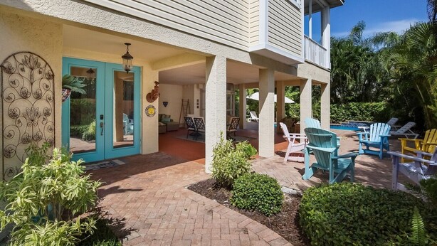 A two-story house with a covered patio area featuring outdoor seating and a pool. - Sunkissed 3 Bedroom Townhouse by RedAwning (Holmes Beach)