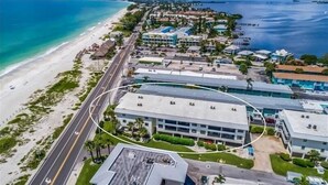 Eine Luftaufnahme eines Küstenhotels mit Strandlage, einem Parkplatz und einer Straße, die zum Strand führt.