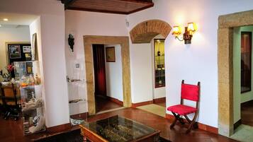 Uma sala de estar ampla com uma mesa de centro de vidro, uma cadeira vermelha e um arco de pedra.