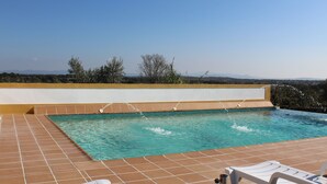 Una piscina con agua azul cristalina, rodeada por un bordeado de baldosas y una pared blanca.