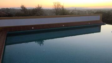 Una piscina al aire libre, sombrillas, sillones reclinables de piscina