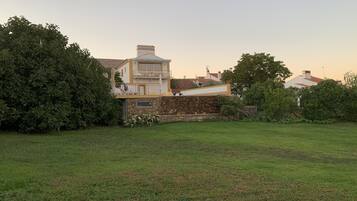 Una casa con un muro de piedra, un balcón y un patio con césped.