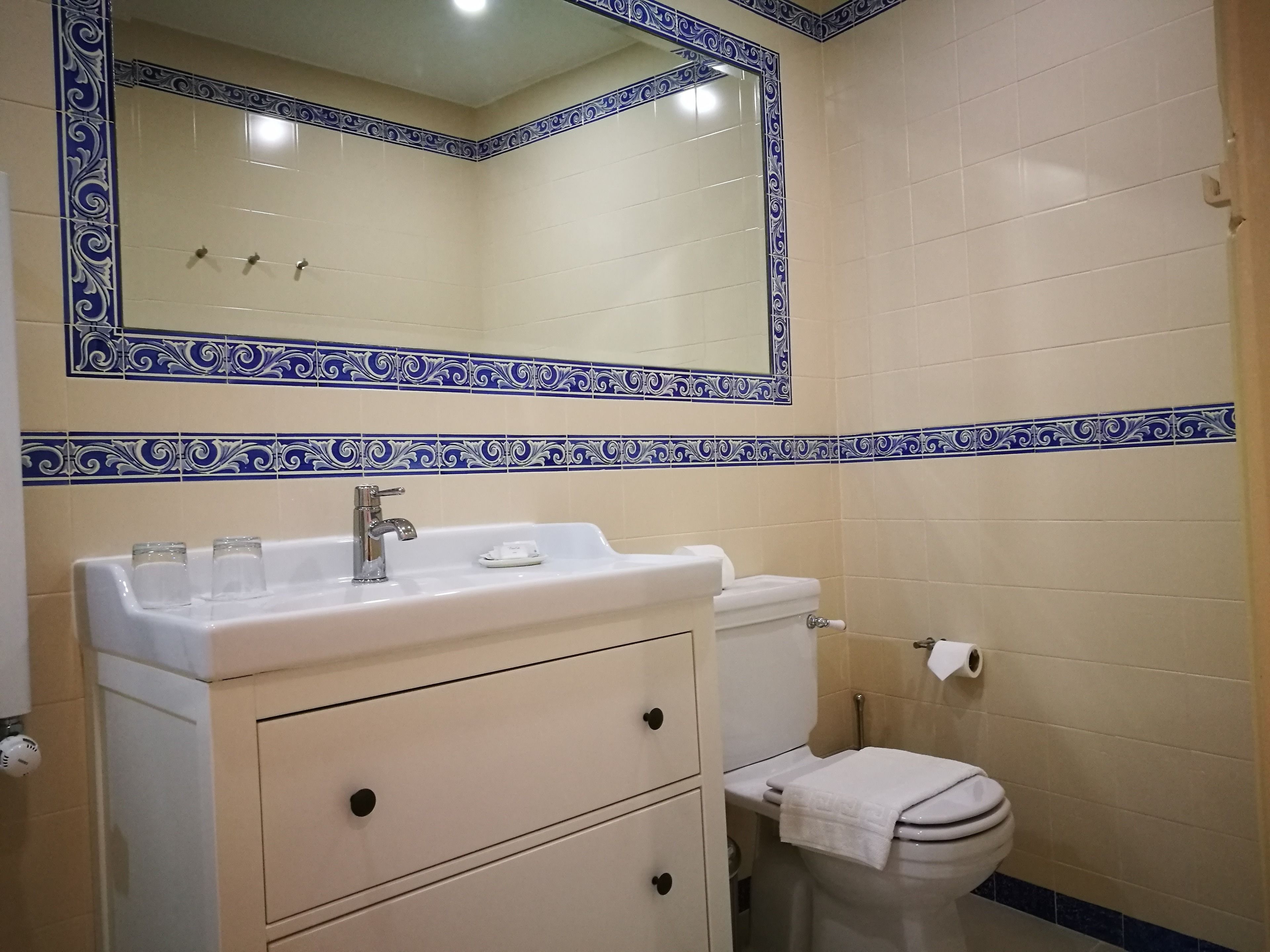 A bathroom with a white sink, mirror, and toilet.