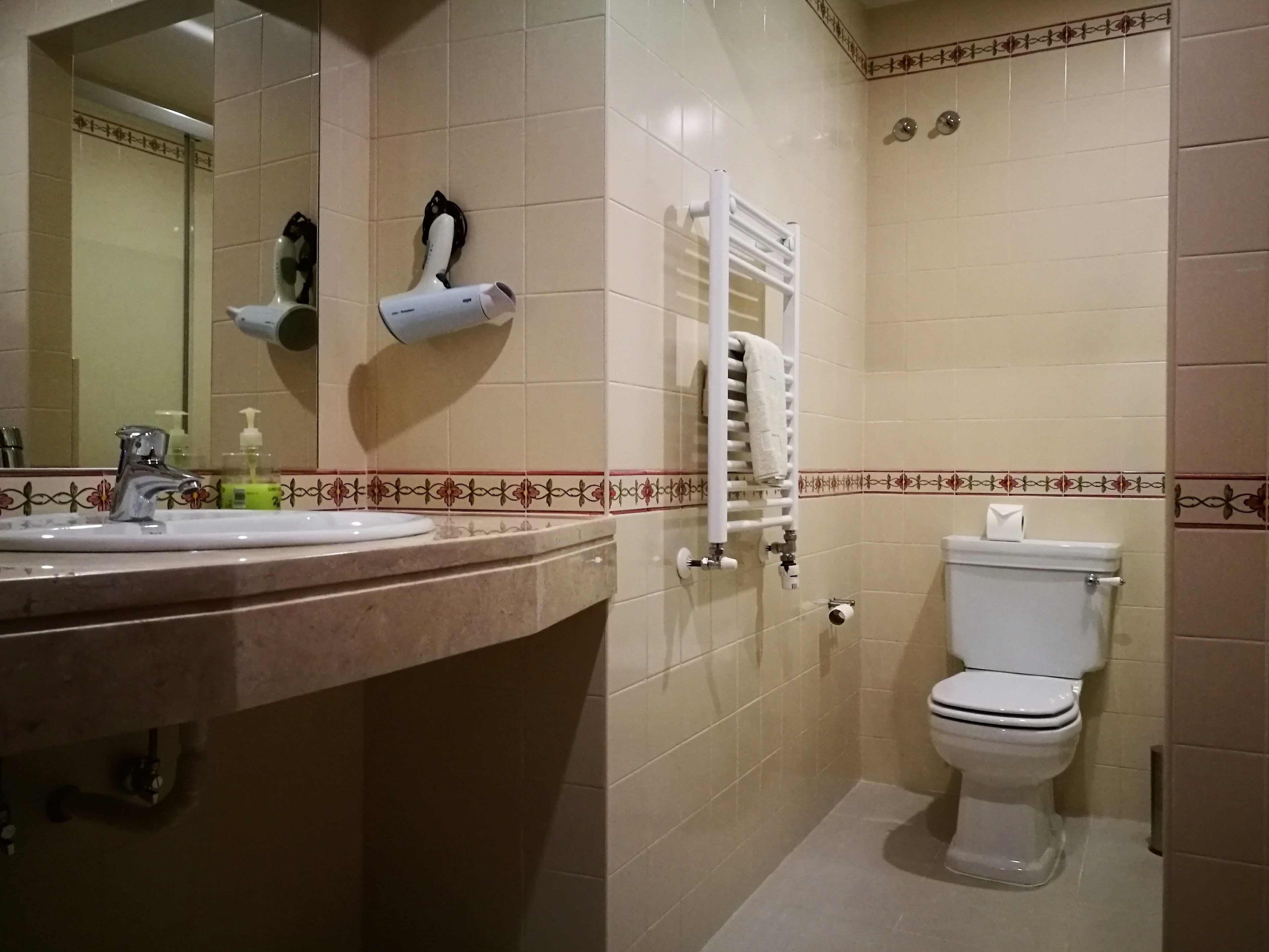 Een badkamer met een wastafel, spiegel, toilet en handdoekhouder.