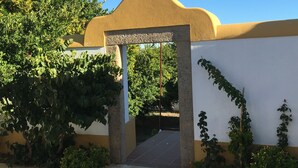 Fachada de un edificio color beige, con un arco de piedra y cielo azul brillante.