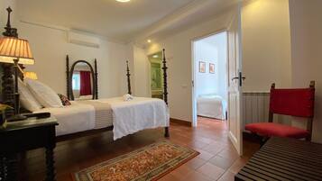 Un dormitorio con cama, mesita de noche, lámpara, espejo y una silla roja.