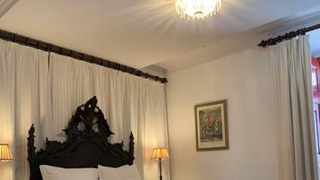 Quarto com cama grande, cabeceira ornamentada, duas luminárias de cabeceira e um quadro na parede.