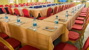 Un salón de conferencias con filas de mesas, cada una con botellas de agua y placas de identificación.