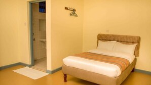 Una habitación con una cama, un perchero y una puerta que da a un baño.