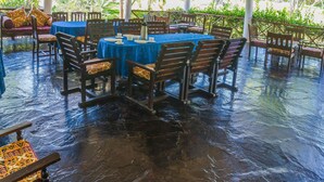 An open-air pavilion with a thatched roof, tables with blue tablecloths, and wooden chairs. - Ocean Breeze Villa (Watamu)