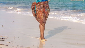 A woman walking on a beach holding a coconut. - Ocean Breeze Villa (Watamu)