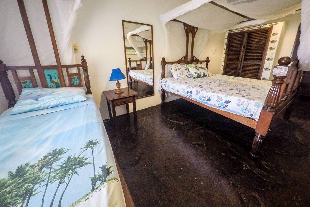 A bedroom with a bed, a nightstand, a mirror, and a wooden headboard.