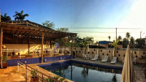 A swimming pool with lounge chairs and a covered seating area. - Hotel do Sol Executive (São Sebastião)
