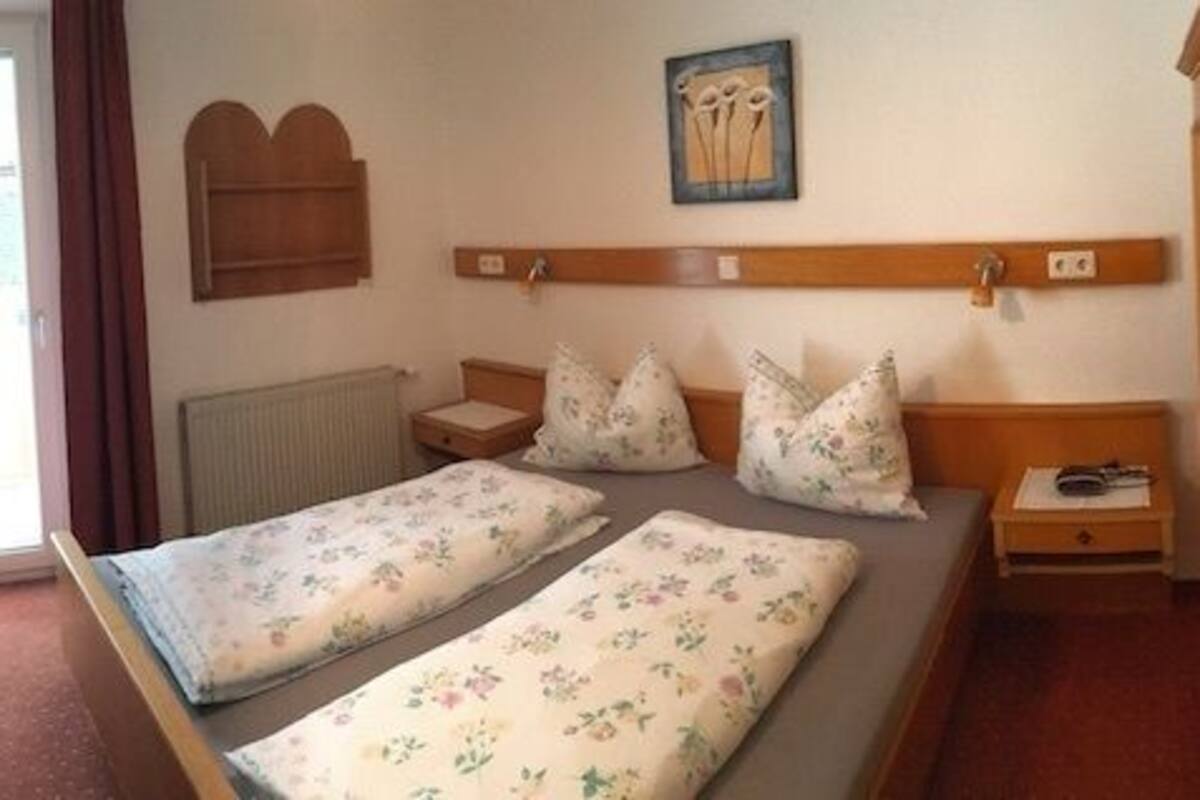 A room with a bed, a sofa, a TV, and a wooden cabinet.