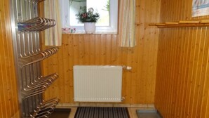 Un sauna con paredes de madera, un banco, un radiador y una ventana con cortinas.