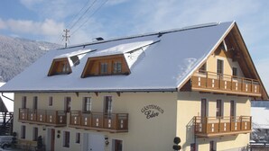 Un edificio de dos pisos con techo inclinado, balcones de madera y un letrero que dice "Gästehaus Eder".
