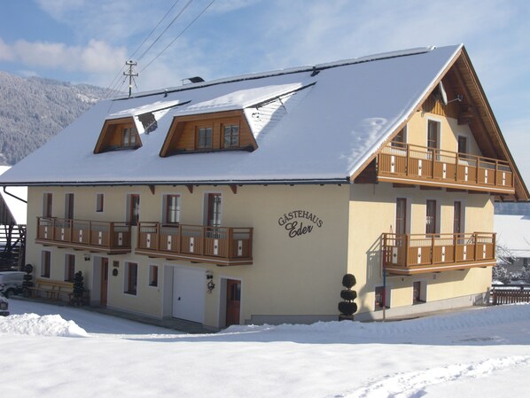 A two-story building with a sloped roof, wooden balconies, and a sign reading "Gästehaus Eder".