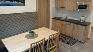 Una cocina compacta con armarios de madera, un microondas y un lavamanos.