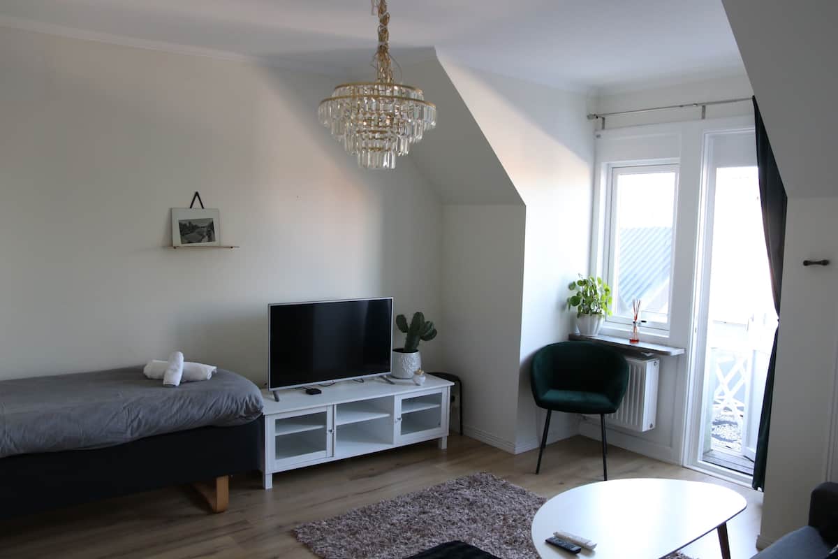 A modern bedroom with a bed, TV, and a small table.