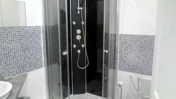Une salle de bain moderne avec une douche à parois de verre, des murs carrelés et un lavabo blanc.