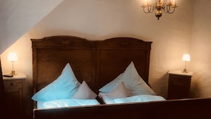 Un dormitorio con cabecera de madera, dos mesitas de noche con lámparas y una araña.