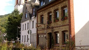 Un edificio europeo tradicional con una torre de reloj, fachada de ladrillo y un letrero que indica un restaurante.