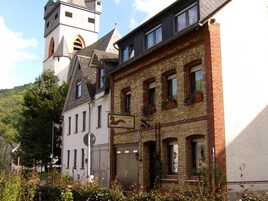 A traditional European building with a clock tower, a brick facade, and a sign indicating a restaurant.