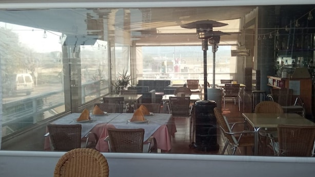 Un comedor interior con mesas y sillas, un ventanal grande y vistas al exterior.