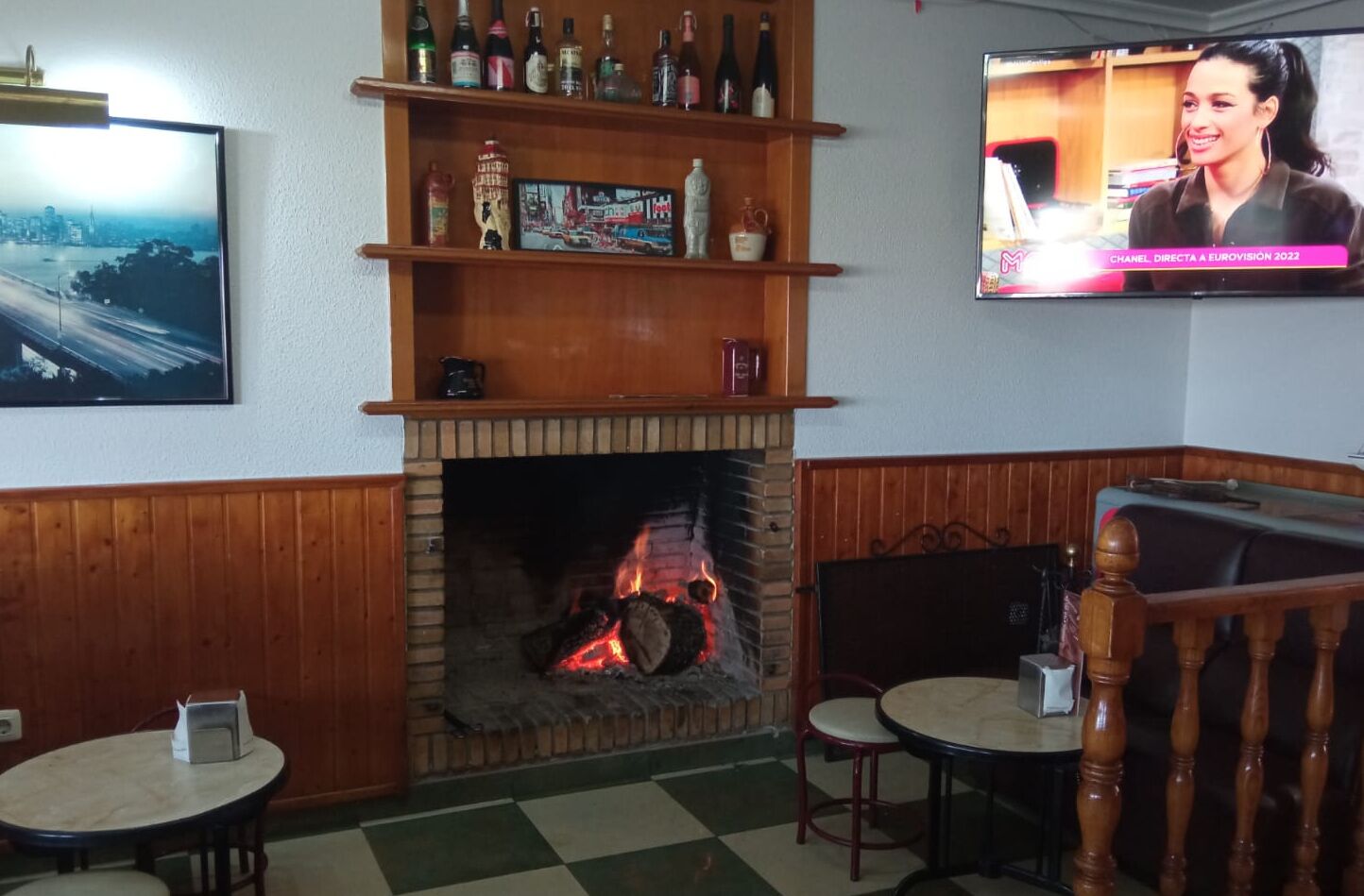 Una habitació acollidora amb una llar de foc, televisió i una zona de bar amb prestatges plens de botelles.
