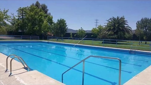 Una piscina al aire libre, sillones reclinables de piscina