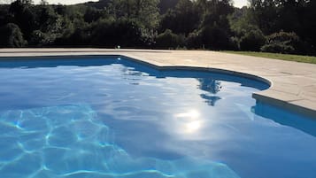 Guests can enjoy a serene swimming pool surrounded by a landscaped area with trees and shrubs.