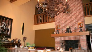 Un comedor con chimenea de ladrillo, una araña y un cuadro en la pared.