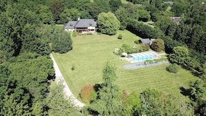Vista aérea de una extensa propiedad con una casa principal, piscina y céspedes bien cuidados.