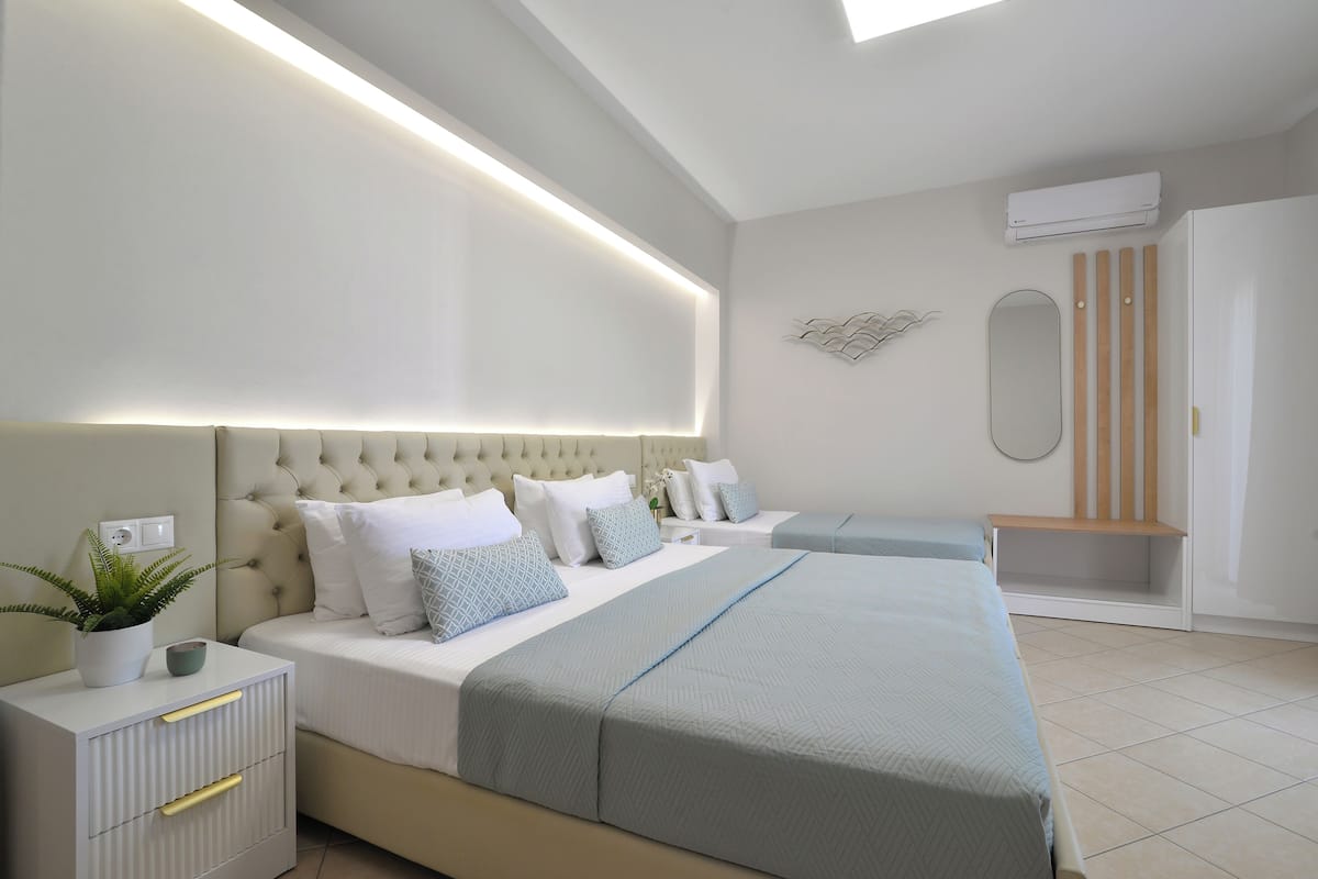 A modern bedroom with a large bed, bedside tables, a potted plant, and a ceiling light.