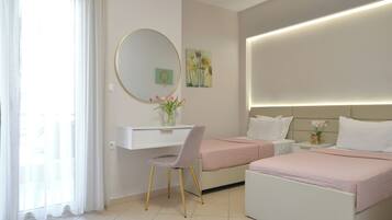 A hotel room with a desk, two beds, a round mirror, and artwork on the walls.