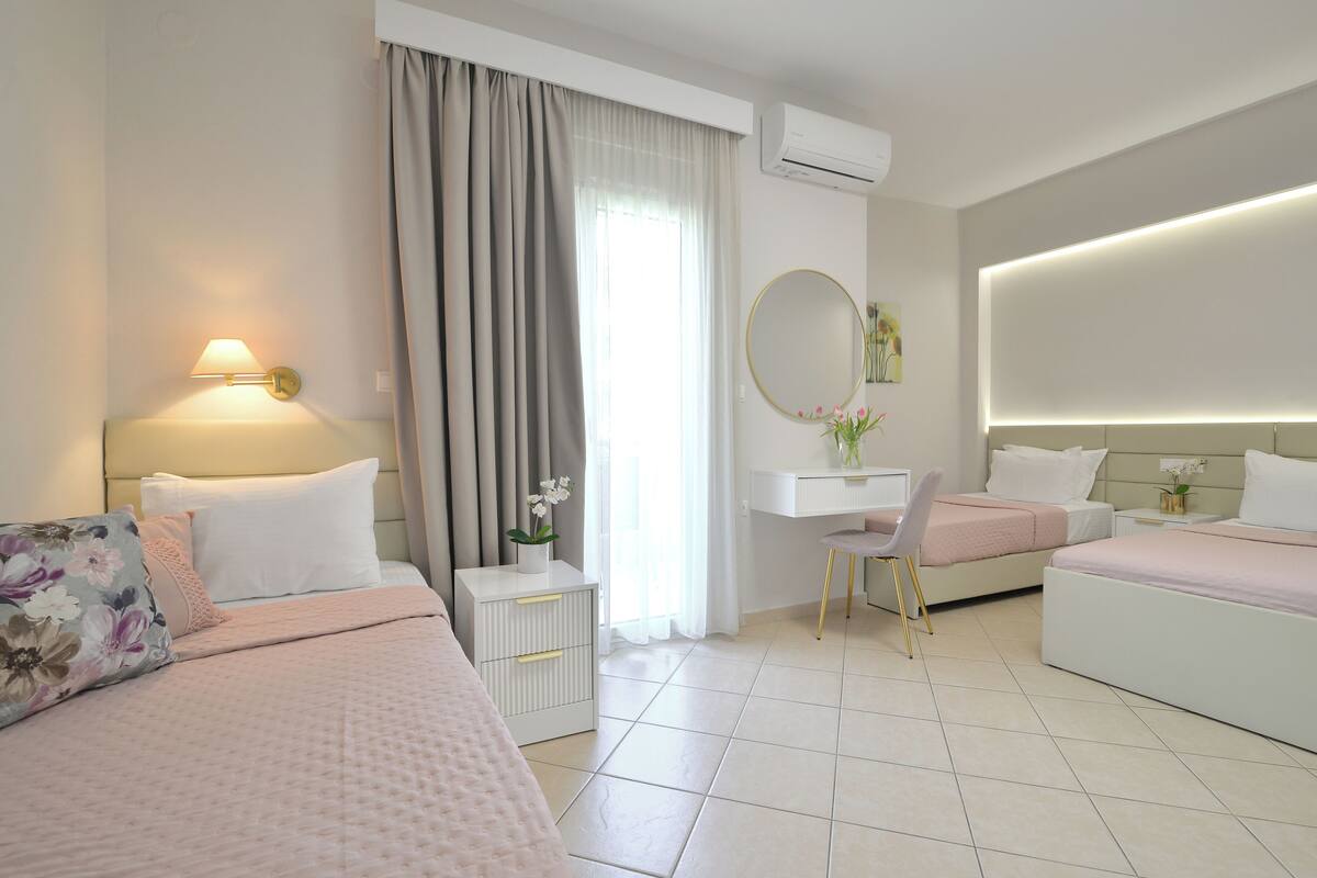 A modern hotel room with two beds, a desk, and a vanity.