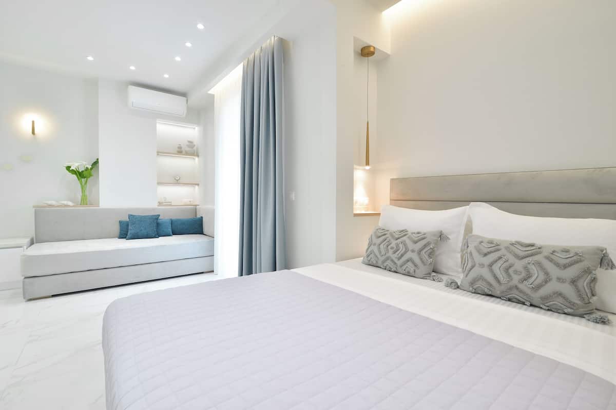 A modern bedroom with a large bed, a sofa, and a built-in shelf unit.