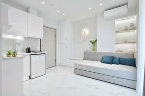 A modern kitchen with white cabinetry, a built-in dishwasher, and a countertop with a coffee machine. - Irida Apartments (Dio-Olympos)