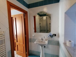 Habitación triple, vistas parciales al mar | Baño | Ducha, artículos de higiene personal gratuitos y secador de pelo