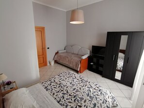 A bedroom with a bed, a wardrobe, a television, and a door. - B&B Eracle (Ercolano)